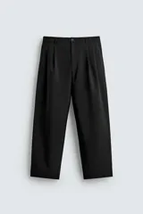 Pantalón negro de corte ancho con pliegues frontales dobles, bolsillos delanteros y traseros de vivo. Cierre frontal con cremallera y botón.
