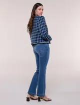 Chaqueta corta de corte estructurado confeccionada en tejido de tweed azul con patrón de cuadros, escote redondo sin solapa, frente abierto, bolsillos falsos y ribetes trenzados con hilos metalizados.