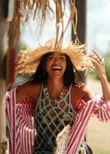 Sombrero de paja color beige con ala ancha y bordes deshilachados, decorado con una banda que incluye apliques de nácar.