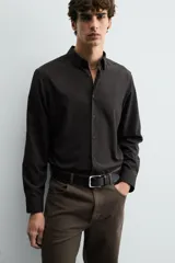 Camisa de corte slim fit, color negro, con cuello italiano, manga larga con puños abotonados y cierre frontal de botones. Confeccionada en tejido de fácil cuidado que minimiza la necesidad de planchado.
