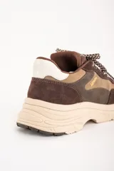 Zapatillas deportivas de cuero marrón con detalles en beige y blanco.