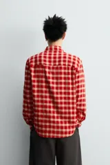 Camisa de corte relajado confeccionada en tejido de mezcla de viscosa y lana con acabado de franela. Presenta un diseño de cuadros en tonos rojo y beige, cuello con botones, cierre frontal de botones y mangas largas con puños abotonados.