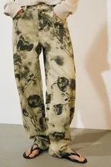 Pantalón jeans ZW Collection de tiro medio y corte balloon, confeccionado en algodón con diseño estampado de flores en tonos oscuros sobre base beige. Cuenta con cinco bolsillos, trabillas para cinto y cierre frontal con cremallera y botón metálico.