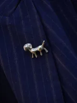 Pin metálico con forma de perro, con acabado plateado y diseño detallado.