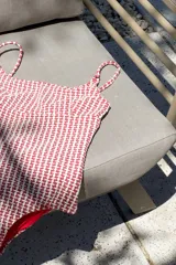 Traje de baño entero color rojo con estampado geométrico en blanco. Diseño con escote en U, tiras finas y corte debajo del busto.