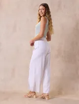 Pantalón blanco de lino con pretina ancha elastizada en punto smock, pierna ancha y ruedo con tajo.