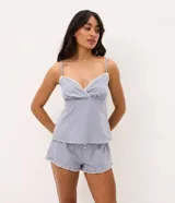 Pijama short doll de dos piezas confeccionado en algodón, con estampa de cuadros vichy en tonos azul y blanco. La musculosa presenta breteles finos, escote corazón con delicado encaje blanco y silueta fluida. El short cuenta con cintura elástica, pequeño moño frontal y terminación ondulada en el ruedo.