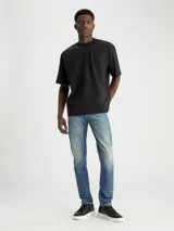 Jeans slim taper de algodón azul con lavado medio, tiro bajo, cinco bolsillos y cierre con cremallera.