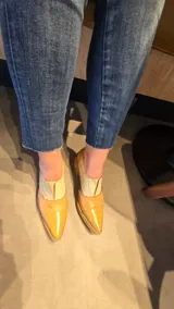 Zapatos de cuero color tostado con puntera fina y tacón bajo, estilo botineta destalonada con laterales abiertos y paneles elásticos en el empeine.