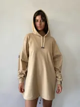 Hoodie oversize color beige, con capucha, cordones ajustables y puños elásticos. Presenta un diseño liso con una pequeña etiqueta de marca en la manga.