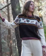 Sweater de punto en lana merino, con diseño de bloques de color en marrón, crema y fucsia. Presenta detalles de bordados artesanales y motivos jacquard en el pecho y las mangas, cuello redondo y mangas largas.
