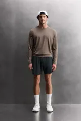 Short deportivo de entrenamiento en tejido técnico ligero y elástico, con cintura elástica ajustable mediante cordón. Presenta bolsillos frontales, un bolsillo trasero con cierre y aberturas laterales en el bajo. Incluye un pequeño logo estampado en la pernera.