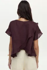 Blusa de lino color beige, de manga corta con volados, cuello redondo y espalda cruzada con volados.