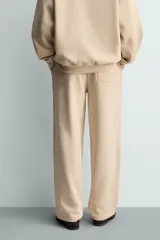 Pantalón jogger de corte relajado y pernera ancha, confeccionado en tejido de algodón con interior perchado. Presenta cintura elástica con cordón interior, bolsillos laterales y un bolsillo trasero de plastrón.
