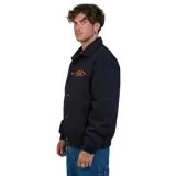 Campera tipo coach negra con cierre frontal de botones metálicos, cuello clásico y puños elásticos. Presenta un estampado bordado en color naranja en el pecho con la inscripción Volcom Stone Company.