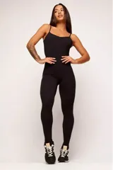 Jumpsuit deportivo de una pieza, color negro, con breteles finos, escote recto y diseño ajustado al cuerpo. Confeccionado en poliamida de alta performance con efecto levanta glúteos.