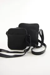 Morral bandolera de cuero genuino color negro, de diseño compacto y silueta rectangular, con bolsillo frontal con cierre y correa ajustable para el hombro.