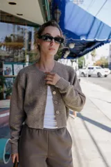 Chaqueta de punto de cuello redondo y manga larga, con cierre frontal de botones y acabados en rib.