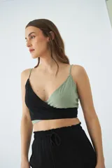 Blusa corta tipo top con diseño cruzado en escote en V, confeccionada en combinación de colores negro y verde. Presenta tirantes finos ajustables y detalle de grifa de cuero.