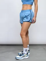 Short de entrenamiento Umbro color celeste con ribetes en azul marino y logo de la marca estampado en el frente. Presenta cintura elástica y paneles laterales de malla.