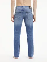 Pantalón de jean azul de corte slim fit, tiro bajo, con lavado vintage y diseño de cinco bolsillos.