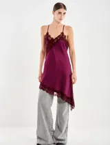 Vestido corto de satén color bordó, con tirantes finos regulables y escote en V. Presenta aplicaciones de encaje en el escote y en el bajo asimétrico, con una silueta fluida y holgada.