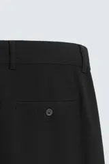 Pantalón chino de corte slim fit, confeccionado en tejido elástico. Presenta bolsillos frontales, bolsillos traseros de vivo con botón y cierre frontal con cremallera y botón.