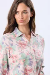 Camisa de jersey de algodón suave, con estampado floral en tonos pastel de rosado, verde y lila. Tiene cuello camisero, cierre frontal con botones y mangas largas.