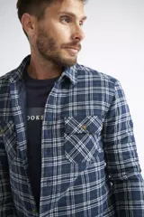 Sobrecamisa de viyela para hombre con estampado de cuadros en rojo y negro. Presenta cierre frontal con botones, bolsillos en el pecho con solapa y botón, y un interior capitoneado para mayor abrigo. Cuenta con un logo en grifa de cuero.