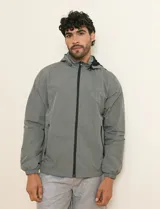 Campera impermeable gris con capucha, cierre frontal y bolsillos laterales con cremallera.