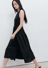 Vestido midi de corte evasé confeccionado en mezcla de lino y viscosa. Presenta cuello de pico, tirantes anchos, cierre frontal con botones y cinturón desmontable a tono para ajustar la cintura.