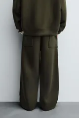 Pantalón de corte wide fit confeccionado en tejido técnico con efecto neopreno. Presenta cintura elástica ajustable con cordón, perneras anchas con costura frontal, bolsillos laterales y bolsillos traseros de plastrón.
