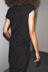 Top negro de manga corta y cuello subido, con detalle de nudos y frunces distribuidos en el frente y laterales, creando textura.