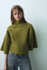 Jersey de punto color verde oliva, con cuello subido y mangas anchas tipo acampanadas.