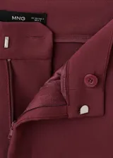 Pantalón de vestir color bordó, de tiro alto y diseño recto, con bolsillos laterales y cierre oculto con botón, gancho y cremallera.