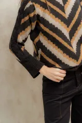 Sweater de punto jacquard con diseño de chevron en tonos celeste y marrón. Presenta cuello redondo, corte holgado y mangas largas con hombros abullonados.