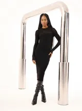 Vestido midi negro de tejido de punto acanalado, con cuello redondo y mangas largas. Presenta un panel de tejido calado en la parte superior del pecho.