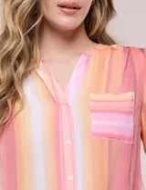 Blusa de gasa Zac & Rachel con estampado de rayas verticales en tonos rosados, amarillos y blancos. Presenta escote en V con cuello mao, cierre frontal con botones, un bolsillo aplicado en el pecho, mangas largas con presilla para regular el largo y detalle de nudo en el dobladillo inferior.
