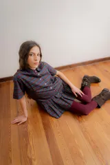 Vestido corto de estilo camisero con estampado de cuadros en tonos azul, verde y bordó. Presenta cuello clásico, cierre frontal con botones y falda tableada con corte a la cadera.