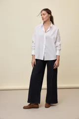 Camisa celeste de corte oversize, con mangas largas, cuello camisero y cierre frontal de botones.