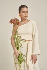 Top color crema de corte cropped, con un solo hombro y manga larga acampanada.