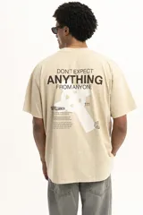 Remera color arena de corte holgado con cuello redondo y manga corta. Presenta un pequeño estampado en el frente.