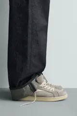 Zapatilla de estilo retro confeccionada en una combinación de piezas de gamuza y cuero sintético en tonos gris y crema, con suela de goma a contraste.
