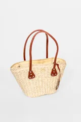 Bolso playero tipo tote de paja color beige con asas de cuero marrón.