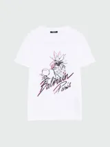 Remera de algodón blanca con cuello redondo y manga corta. Presenta un estampado frontal con diseño de piña y frutas, acompañado por el logo de Balmain Paris en tipografía cursiva con detalles en color rosado.