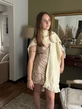 Vestido corto negro con estampado de plumas doradas, escote en V, breteles finos cruzados en la espalda, cut-outs laterales y volado en el ruedo.