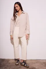 Camisa oversize color arena con rayas verticales marrones, de manga larga y cuello clásico.