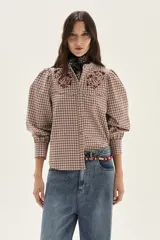 Camisa de manga larga con diseño de cuadros en tonos rosa y bordó. Presenta cuello mao, cierre frontal con botones y detalles de bordados florales en la parte superior del pecho. Las mangas son abullonadas con puños ajustados.