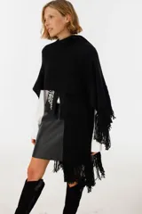 Ruana negra de tejido de punto con flecos y aplique de cuero vacuno con manchas blancas.