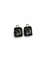 Par de dijes rectangulares hechos a mano en arcilla polimérica negra con destellos dorados y cristal central transparente.